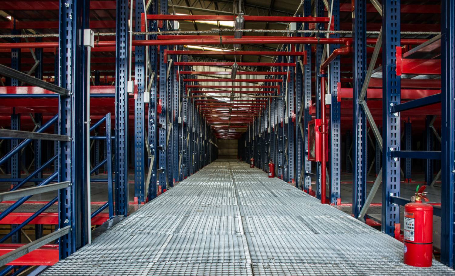 Pasillo central entre racks antisísmicos con pasarelas metálicas para almacenamiento de 112.000 cajas de documentos del Gobierno de Salta.